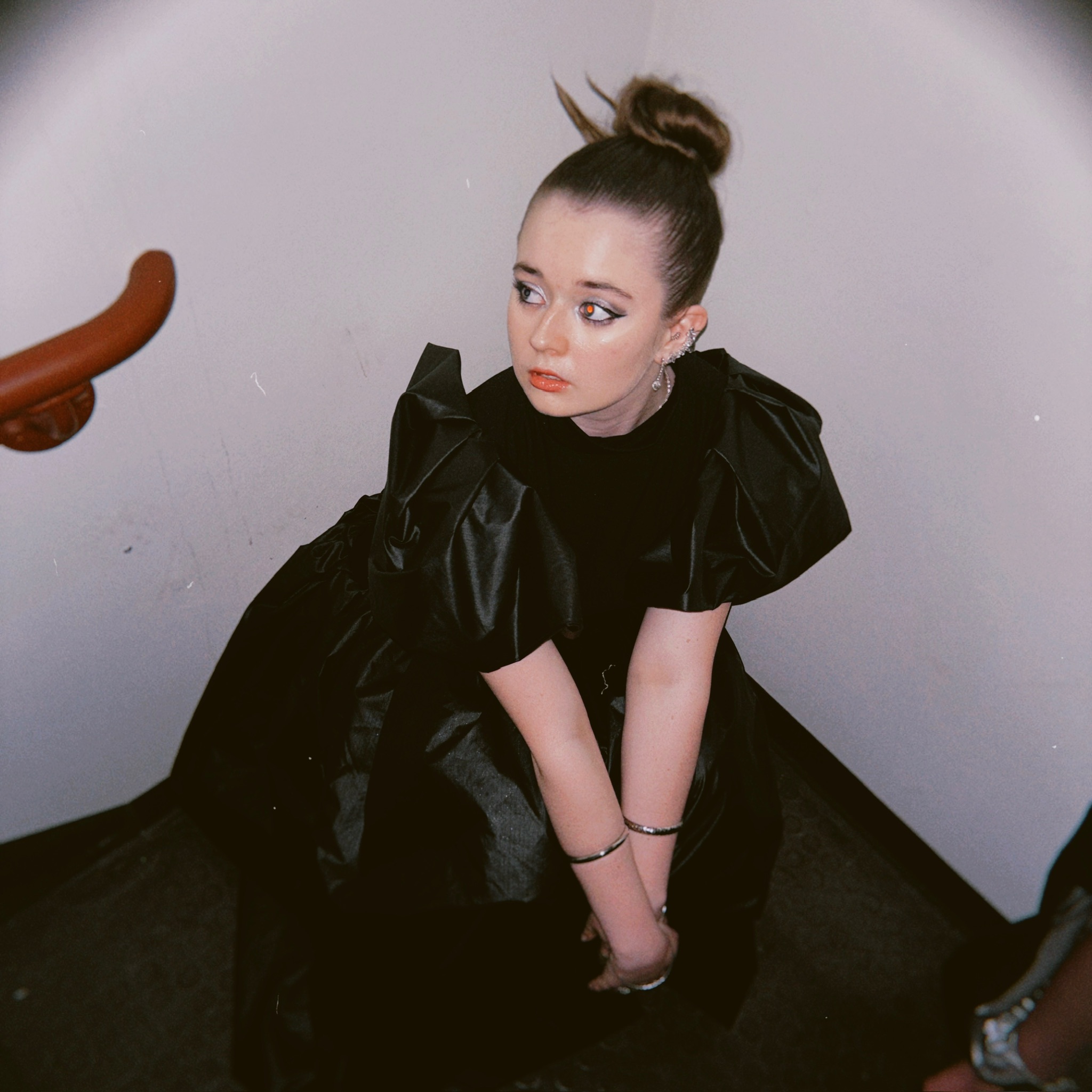 Seriena Rose in a black puff-sleeve gown, crouching, moody editorial portrait