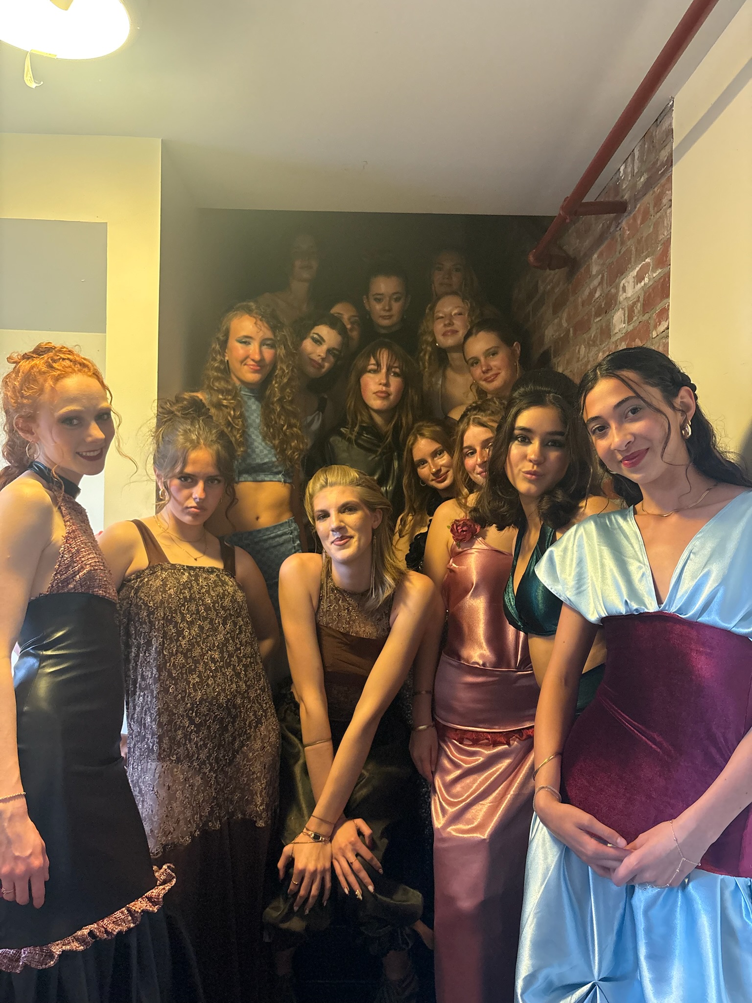 The full group of runway models posing together backstage after the show