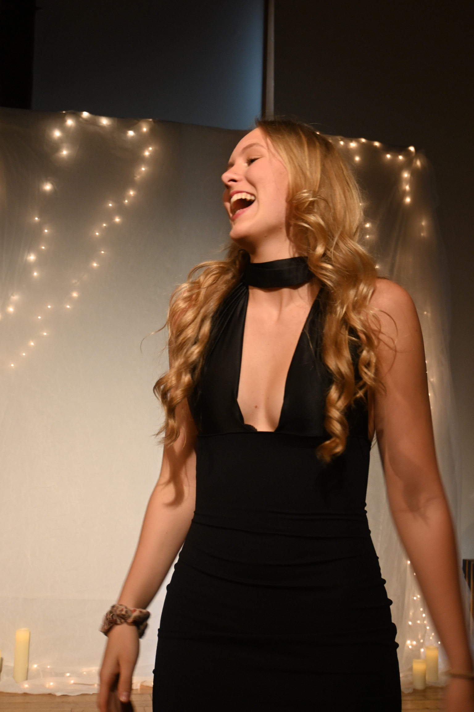 Seriena laughing candidly on stage in a black halter dress