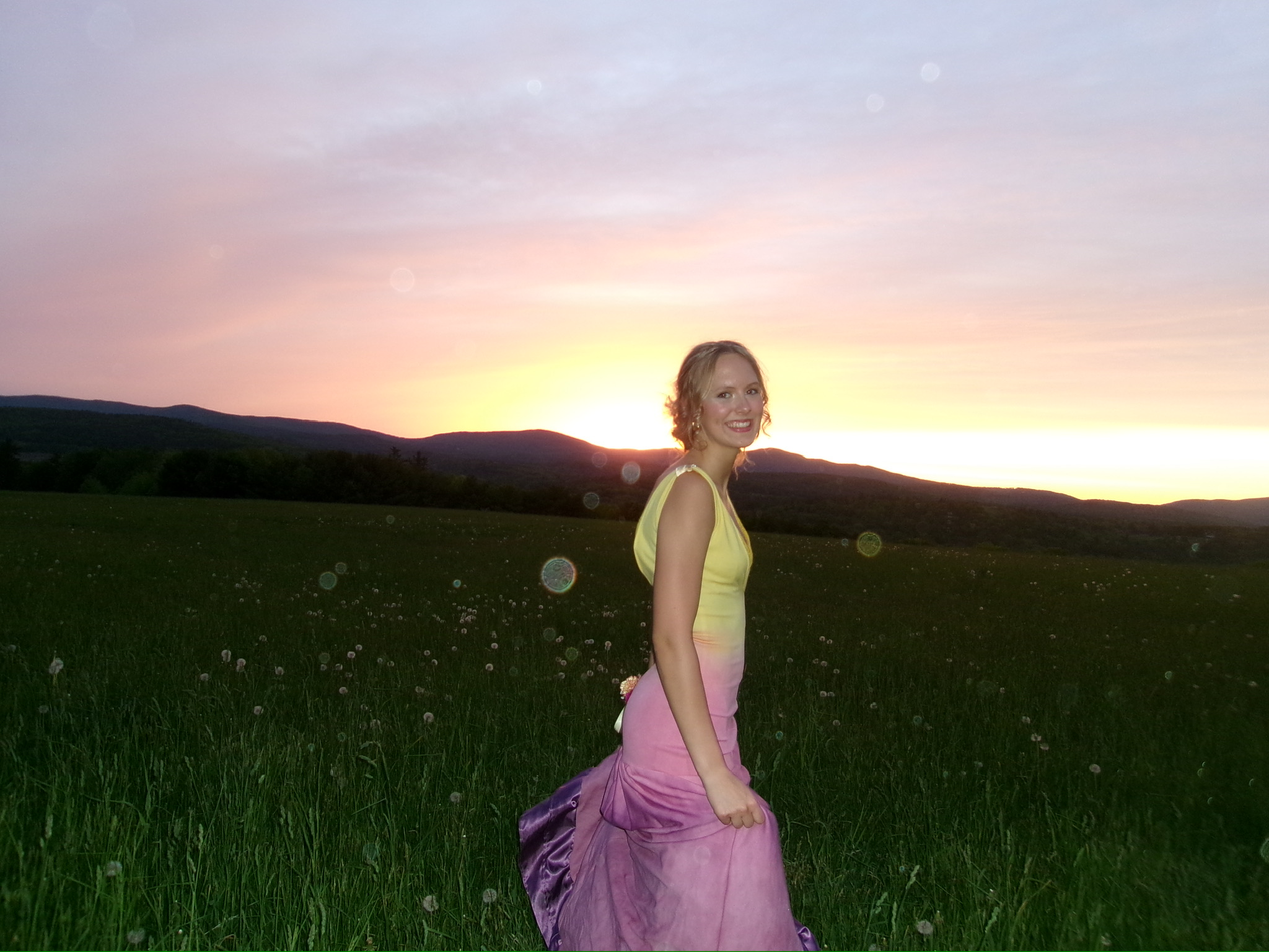 Seriena Rose Ciborski in a yellow-to-pink ombre gown in a grassy field at sunset