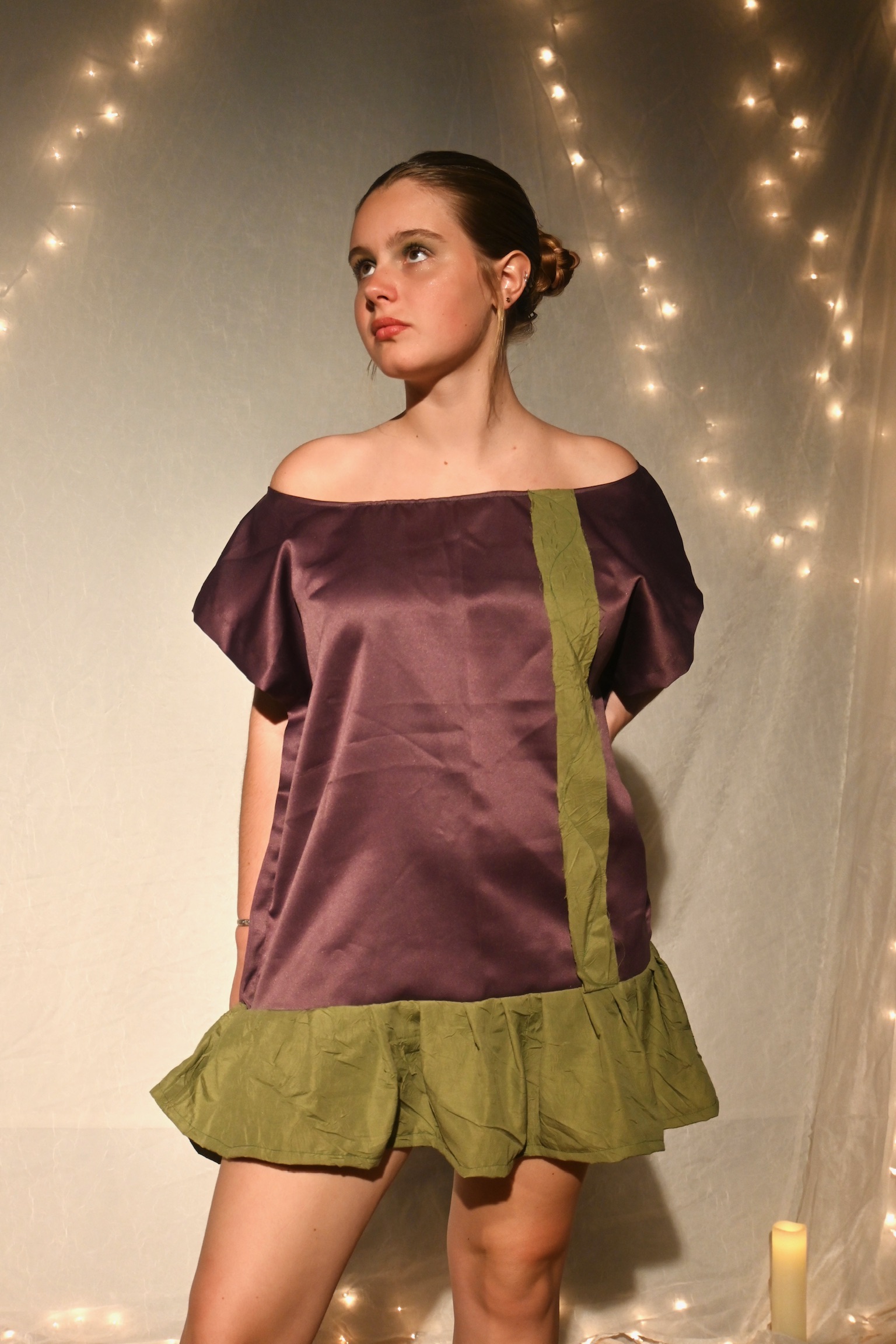 Model in a plum satin off-shoulder dress with an olive green ruffle trim, ENNA runway show