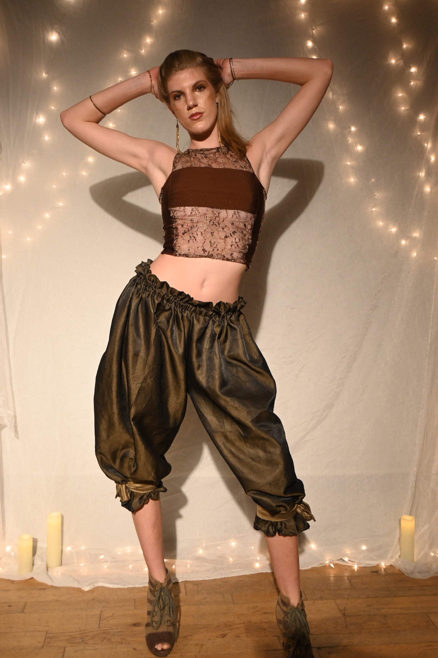 Model in gold harem pants and a brown lace crop top, ENNA runway show