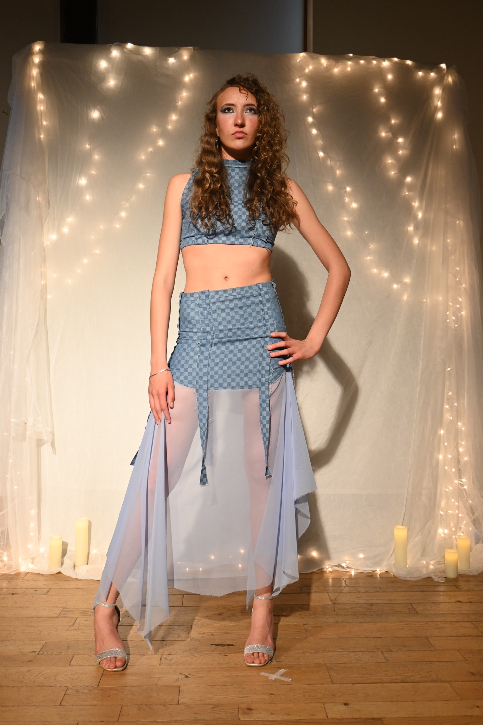 Model in a denim checkered crop top and matching skirt with a sheer mesh train, ENNA runway show