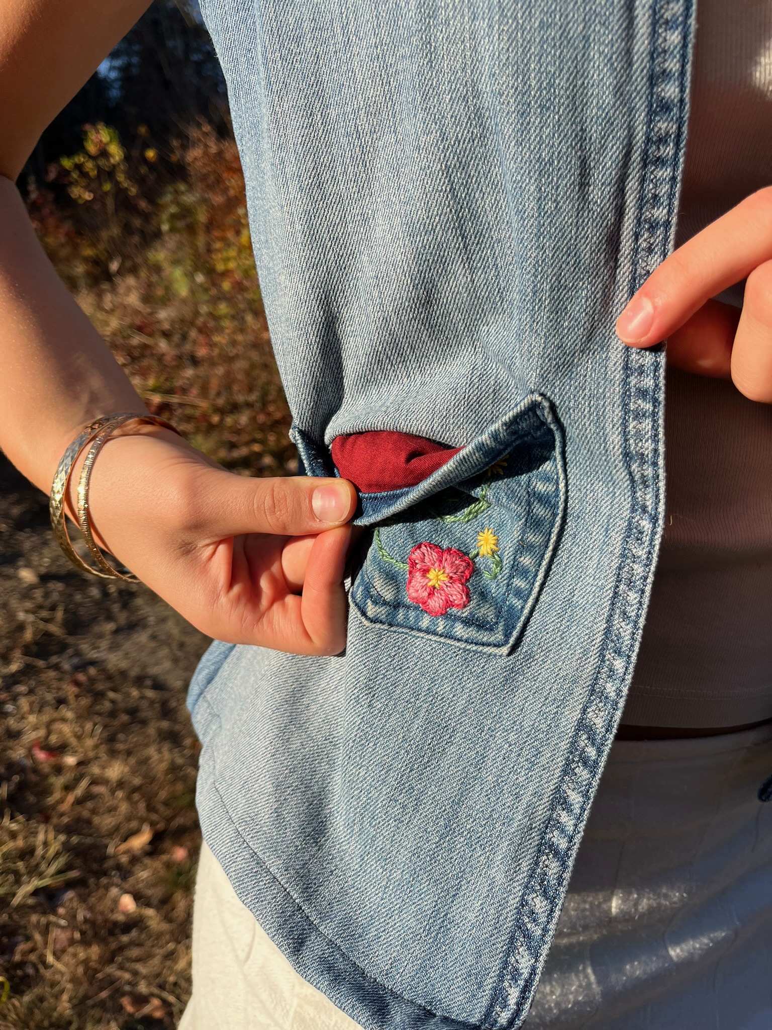 Close-up of hand-embroidered flowers on an upcycled denim pocket, revealing a red fabric lining