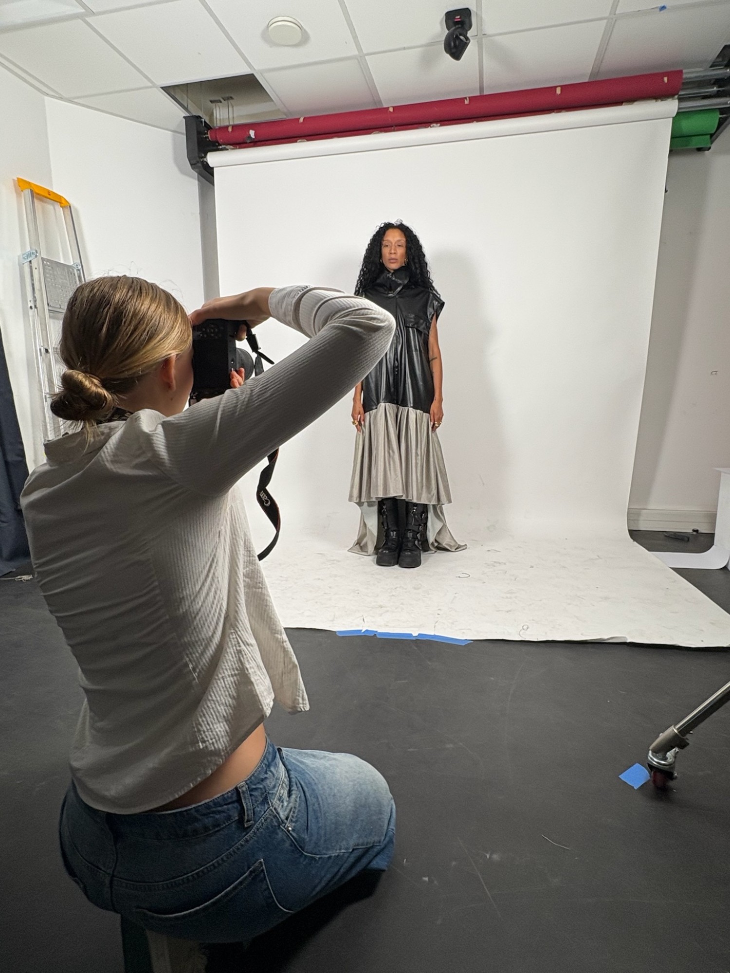 Seriena photographing a model in a black leather-look dress with a flowing silver skirt during a studio shoot