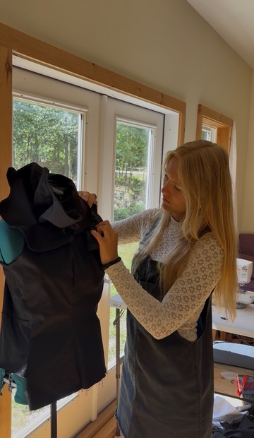 Seriena adjusting a black asymmetrical neckpiece on a dress form for the Carrie-Anne Moss commission