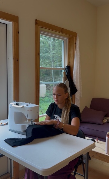 Seriena sewing black fabric at her sewing machine while working on the Carrie-Anne Moss commission