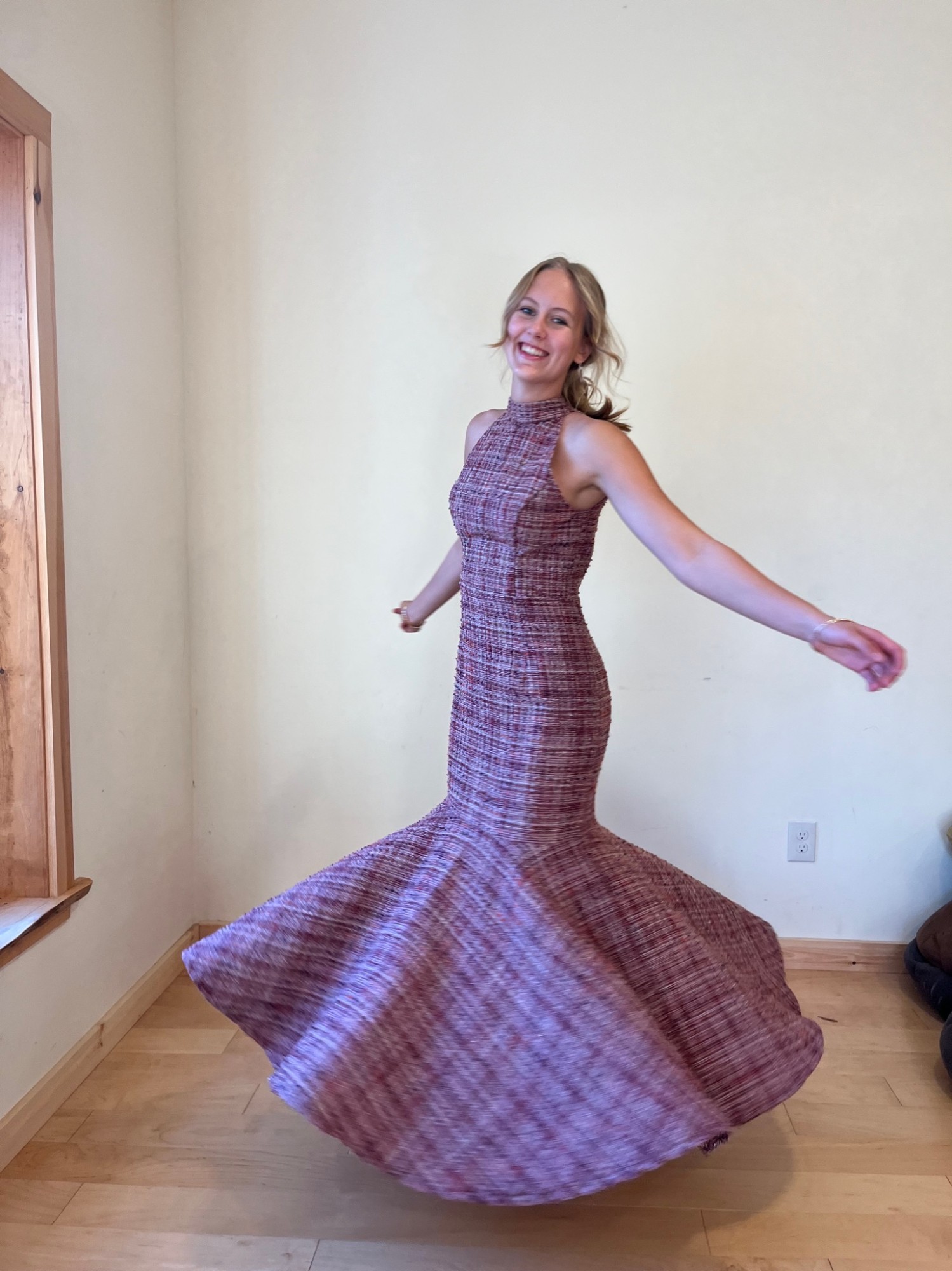 Model twirling in a mauve hand-woven mermaid gown in a sunlit room