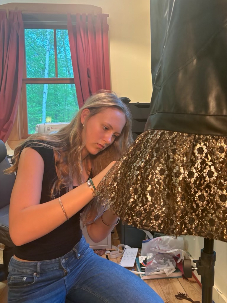 Seriena working on a sequined garment on a dress form in her studio