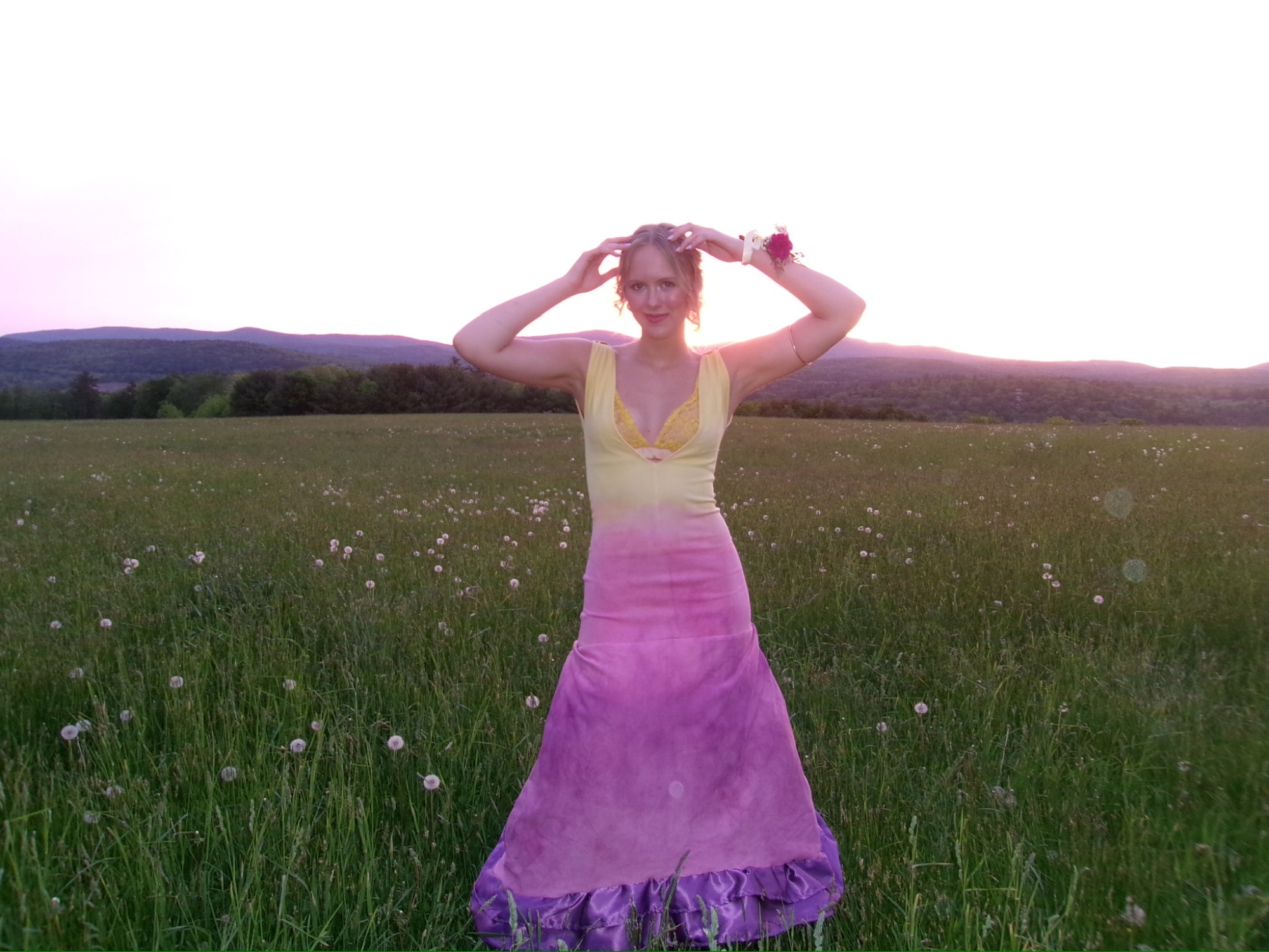 Model in a yellow-to-pink ombre mermaid gown standing in a field at sunset