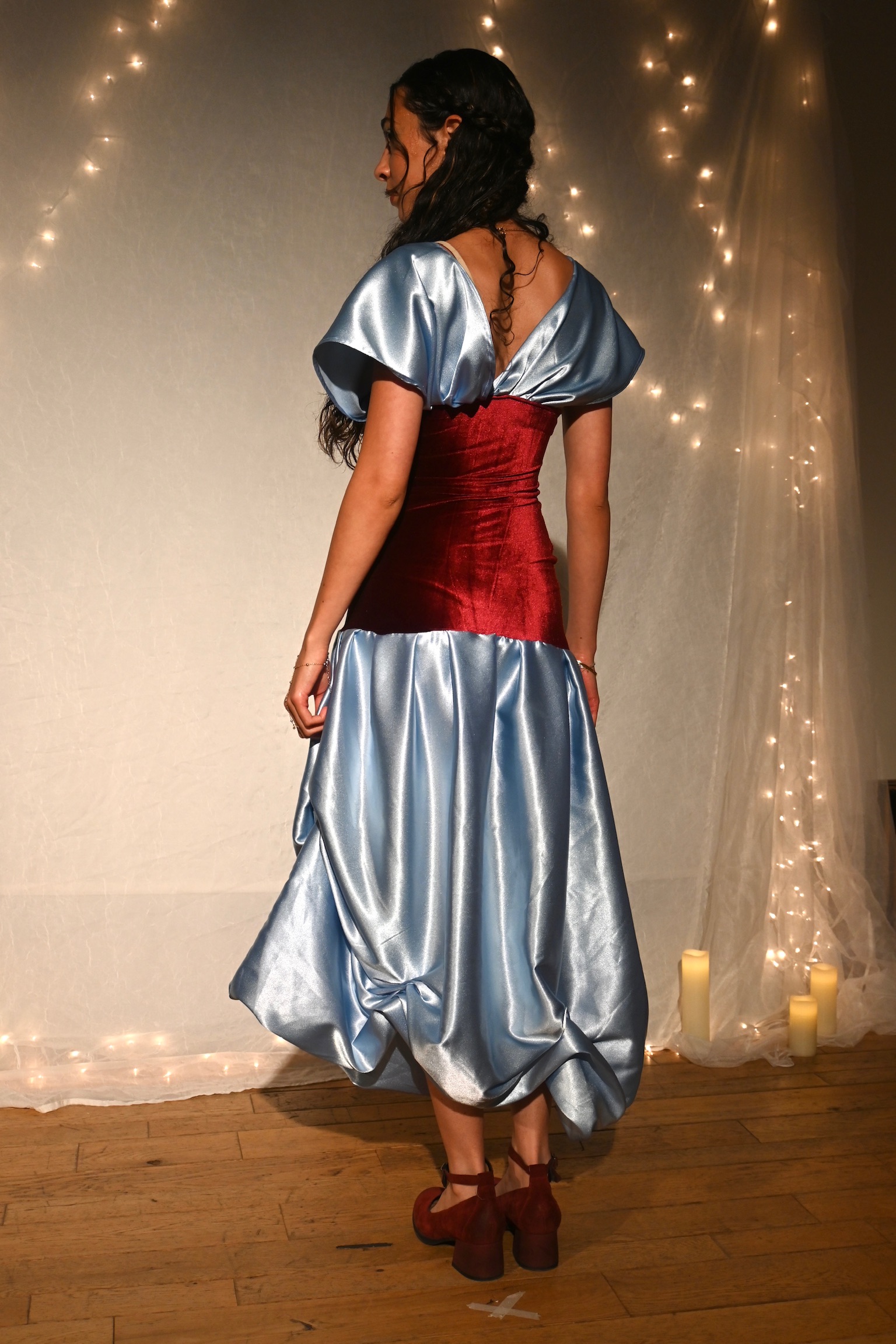 Model in a satin blue puff-sleeve gown with a red velvet bodice, back view, ENNA runway show