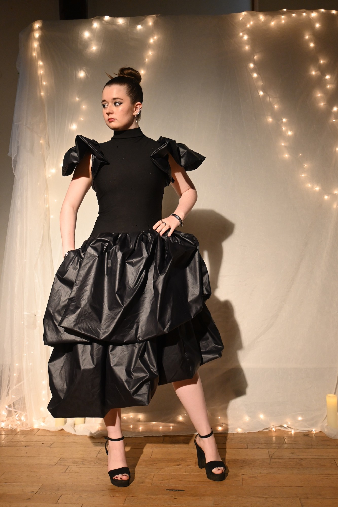 Model in a black turtleneck bodysuit with sculptural shoulders and a tiered black taffeta bubble skirt, ENNA runway show