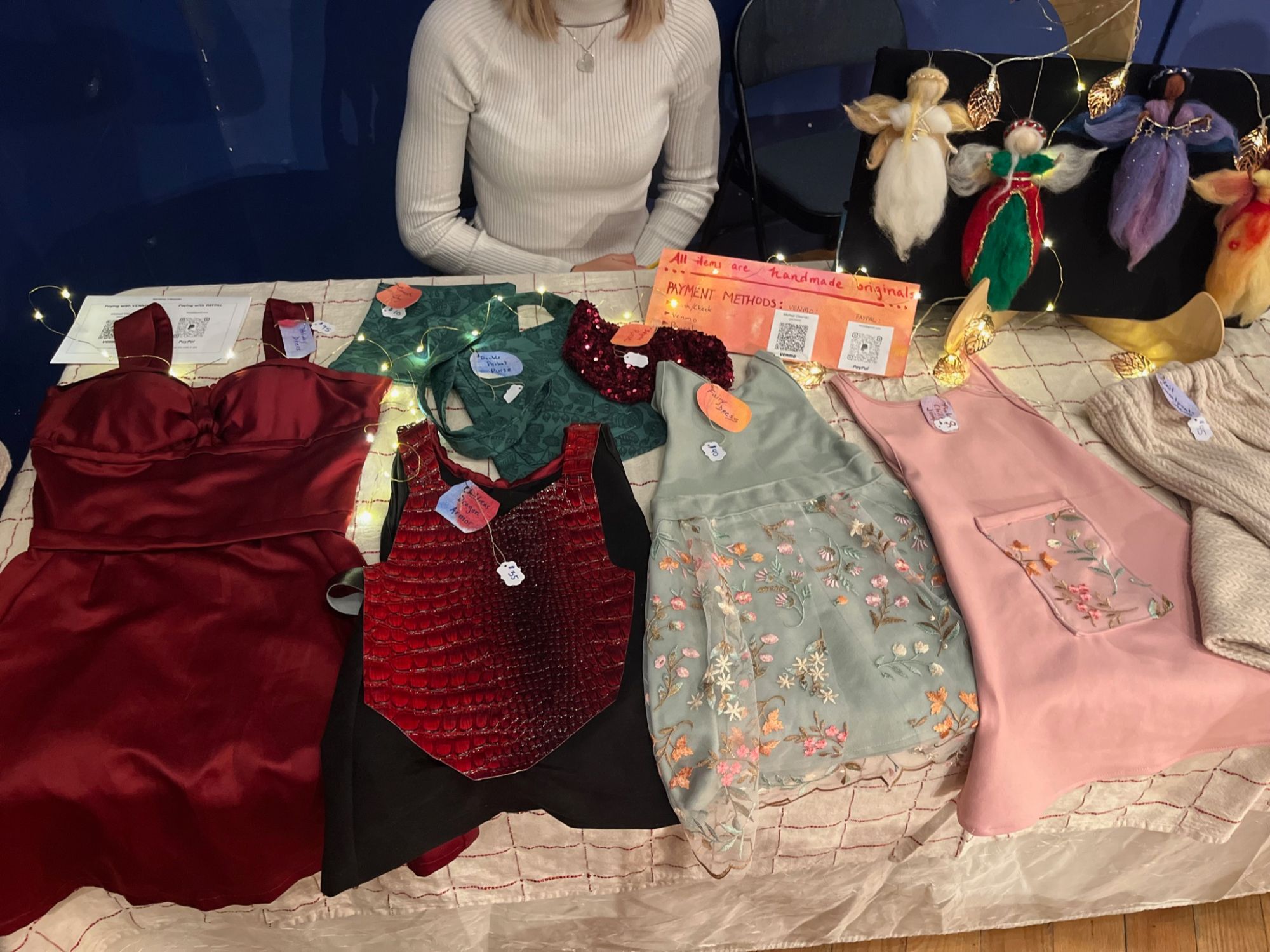 Table display of handmade ENNA clothing with price tags at a craft fair