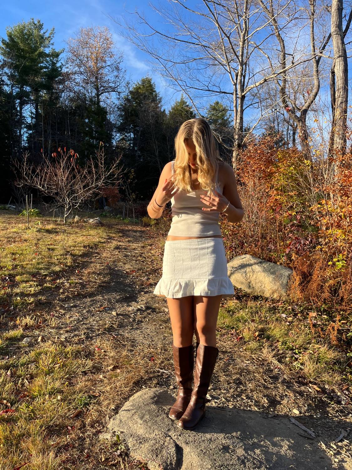 Model outdoors wearing a beige cropped tank and a textured ruffle-hem mini skirt