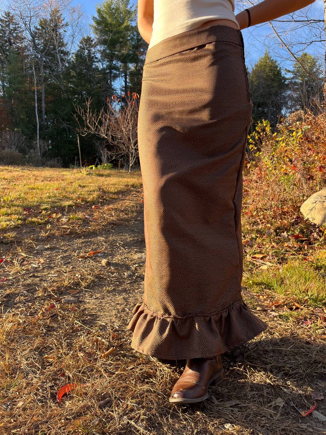 Model outdoors wearing a brown geometric jacquard maxi skirt with a ruffled hem