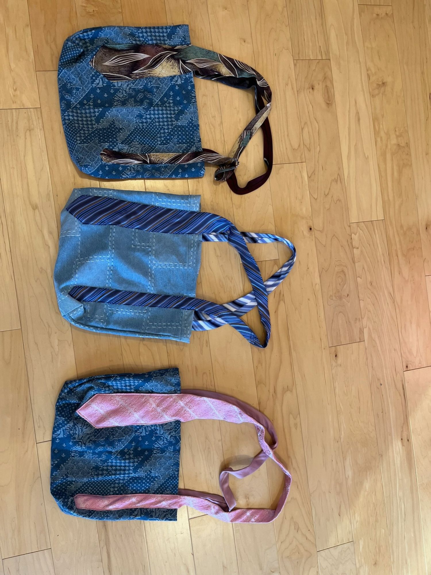Three patchwork tote bags with straps made from upcycled neckties, laid flat