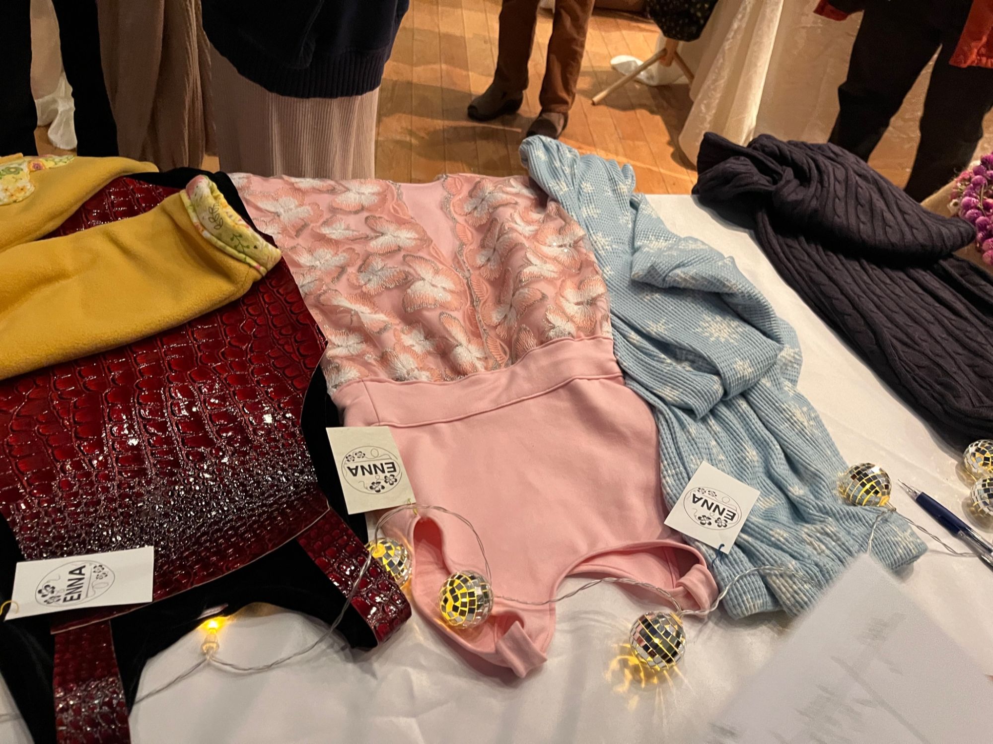 Flat lay of ready-to-wear pieces and ENNA tags with string lights